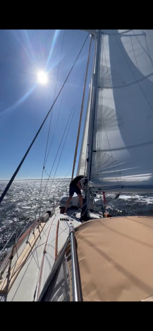 sailor on deck of a sailboat under sail on a clear, sunny day